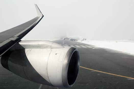 aircraft wing with turbine landing on snow winter runway