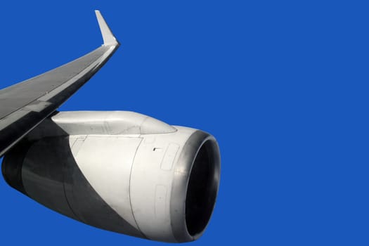 airplane wing with turbine flying on clean blue background