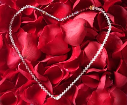 Jewel necklace over bed of red rose petals