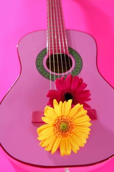 Hippie flower power yellow pink gerbera on guitar still music metaphor