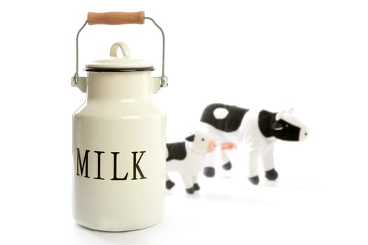 Milk urn white pot with blurred toy cows isolated on white