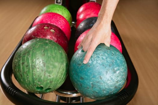 Bowling ball in player man hand in colorful rows