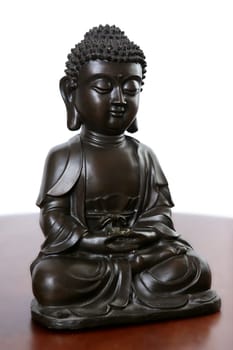 Buddha little black sculpture over red wood table