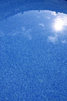 blue tiled swimming pool with sun reflexion summer vacation background