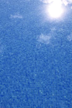 blue tiled swimming pool with sun reflexion summer vacation background
