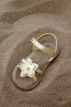 golden star sandal buried in summer beach sand vacation metaphor