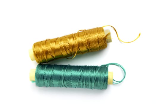 metallic rayon thread line spool in green and golden colors over white