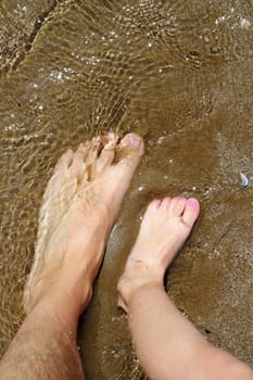 father and children feet on summer sand beach shore wavy water