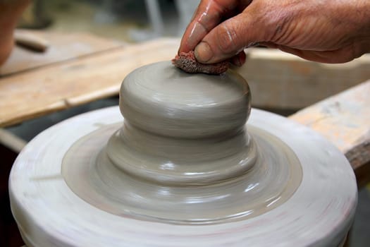 man potter hands working on pottery clay wheel stoneware sponge