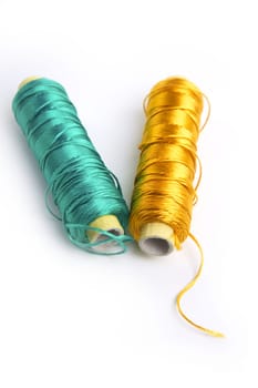metallic rayon thread line spool in green and golden colors over white