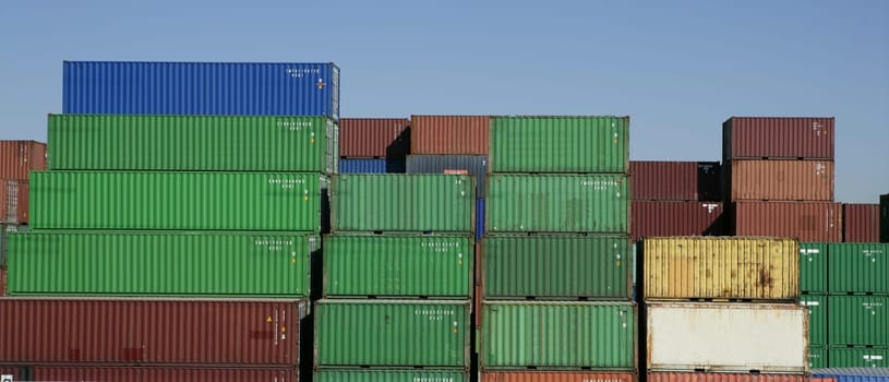 Stacked freight colorful containers on harbour, blue sky