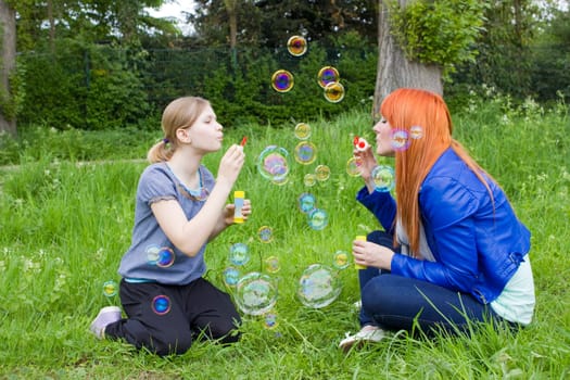 Little girl and young woman blowing soap bubbles