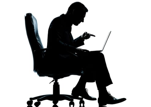 one caucasian business man computer computing pointing sitting in armchair silhouette Full length in studio isolated on white background