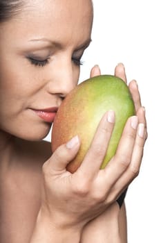 Closeup portrait of beautiful woman smelling fresh mango with eyes closed in studio isolated on white background