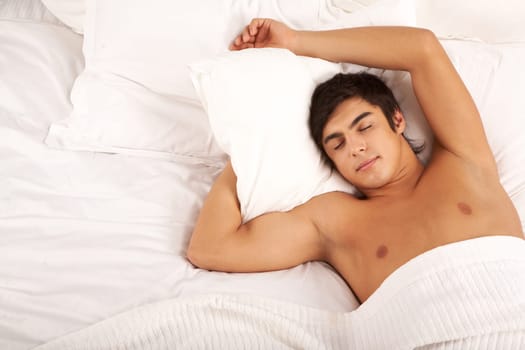 Image of man with one hand under pillow sleeping in bed