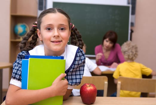 Portrait of happy girl with copybooks looking at camera at school