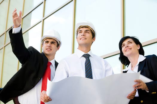 Confident worker pointing at something while explaining new project to his colleagues