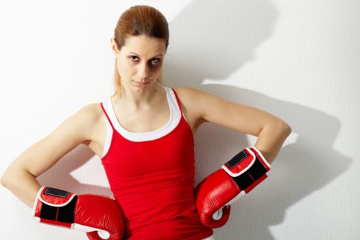 Portrait of young woman in red boxing gloves looking at camera