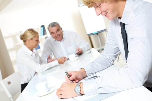 Portrait of confident businessman thinking over business plan with communicating partners at background