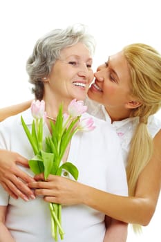 Portrait of pretty woman embracing her senior mother and holding tulips