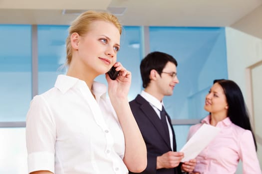 Image of pretty employee speaking on the phone in working environment