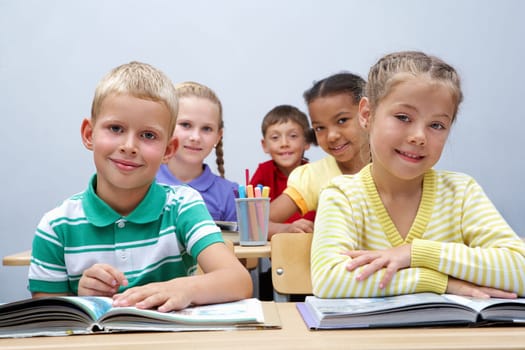 Portrait of pupils looking at page of encyclopaedia at reading lesson