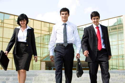 Portrait of confident business group walking outdoors and looking at camera
