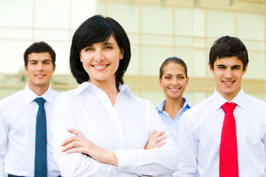 Portrait of pretty woman smiling at camera with business partners at background