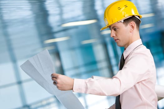 Portrait of confident foreman in helmet learning blueprint