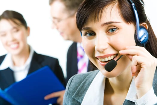 Closeup of young woman with headset looking at camera with smile in working environment