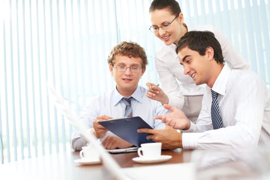 Three business people discussing papers with current results