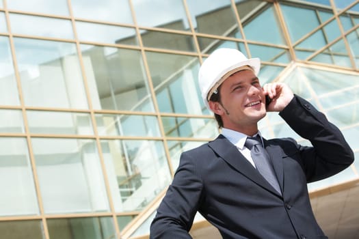 Portrait of confident foreman in helmet calling by mobile phone