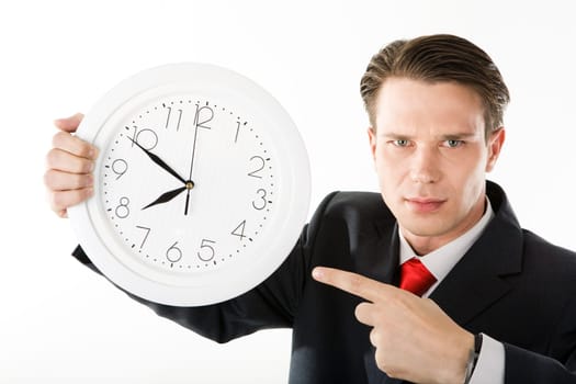 Businessman with serious expression on his face pointing at clock face