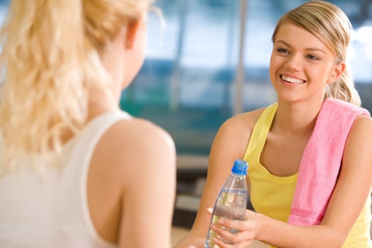 Generous girl giving bottle of water to the friend in front of her