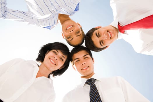 Below view of several successful partners looking at camera with happy smiles