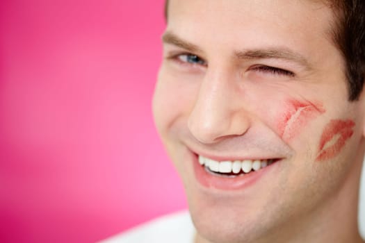 Handsome man with print of lipstick on his cheek winking at camera