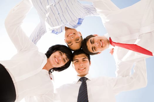 Below view of several successful partners embracing and looking at camera with smiles
