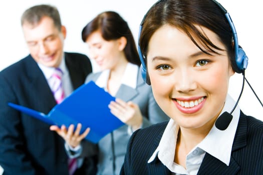 Closeup of young woman with headset looking at camera with smile in working environment