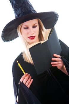 Portrait of young witch reading black book with attention