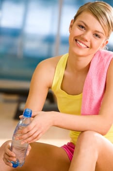 Portrait of happy woman wearing yellow tanktop looking at camera with smile in gym