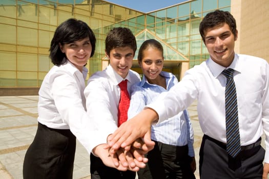 Portrait of business people keeping hands together near the building