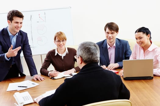 Rear view of aged businessman making report to partners at conference