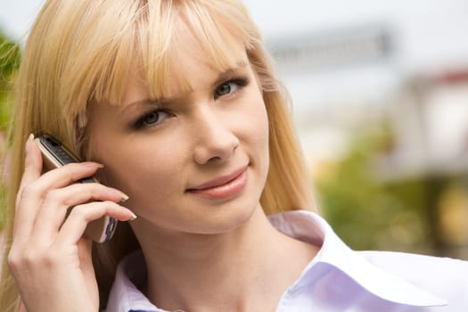 Portrait of modern female holding cell by her ear and looking at camera