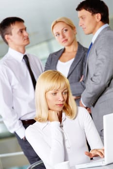 Pretty businesswoman working with laptop on background of communicating partners