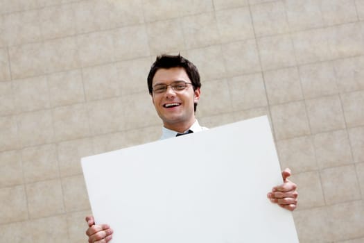 Image of successful male with blank paper looking at camera and smiling