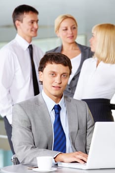 Portrait of businessman working with laptop on background of communicating partners