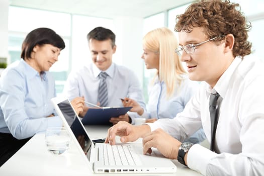 Serious businessman sitting in office and typing in working environment