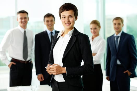 Attractive woman looking at camera and smiling against her business team