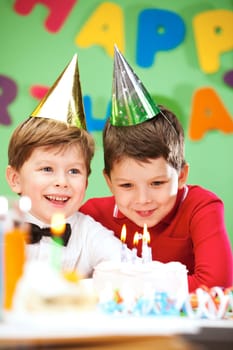Portrait of happy boys on birthday party with cake near by