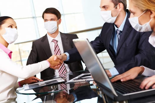 Business partners in protective mask shaking hands after signing contract